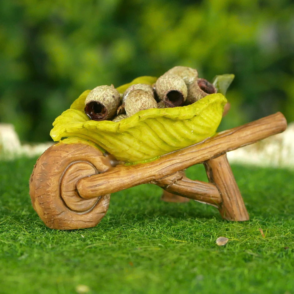 Fairy Garden Wheelbarrow decoration with wood type frame and a green leaf for the barrow. Includes some small gumnuts to fill the wheelbarrow.