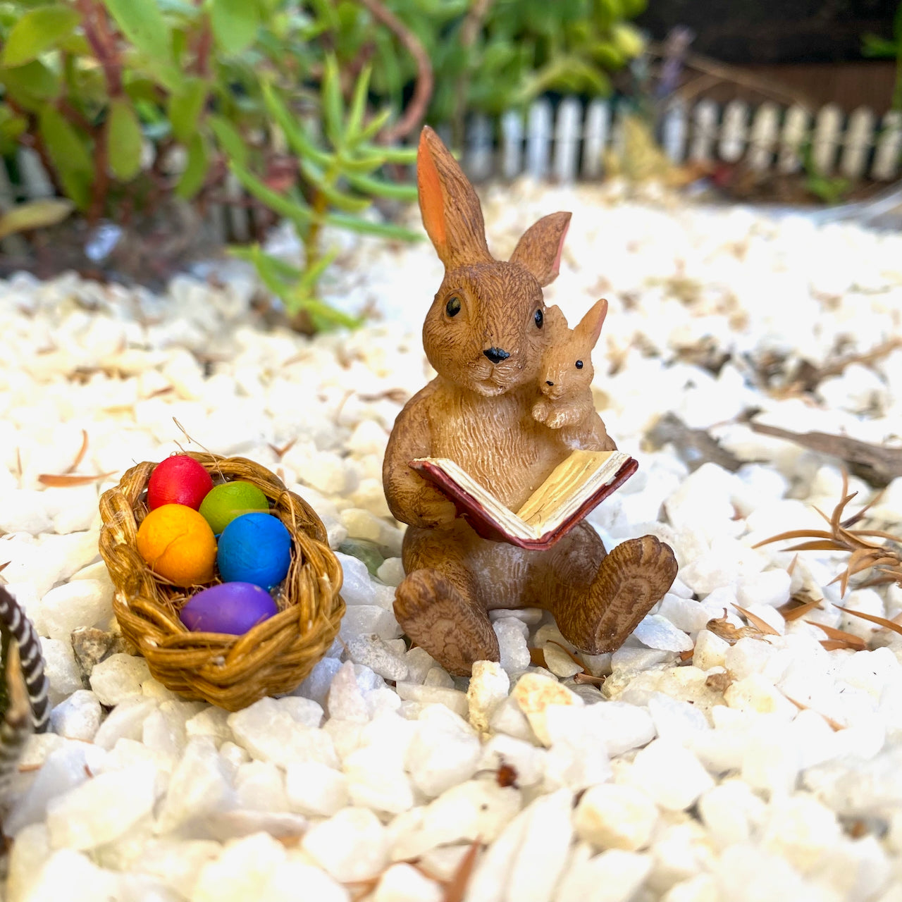 Bunny reading a book to baby bunny with a basket of easter eggs